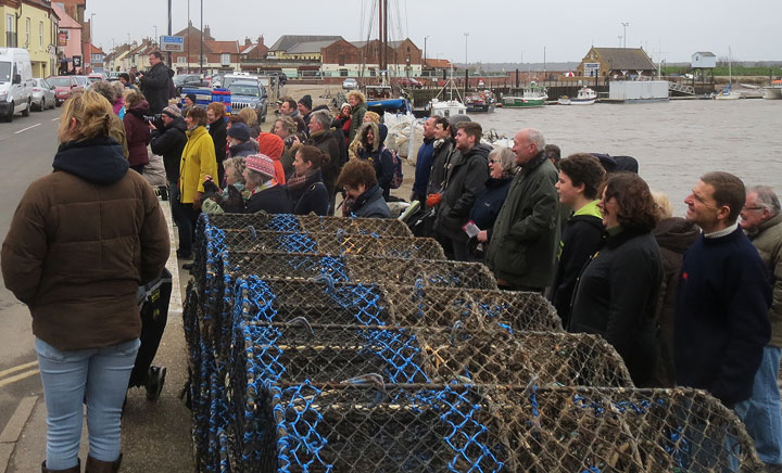 A small crowd on a cold, windy quayside