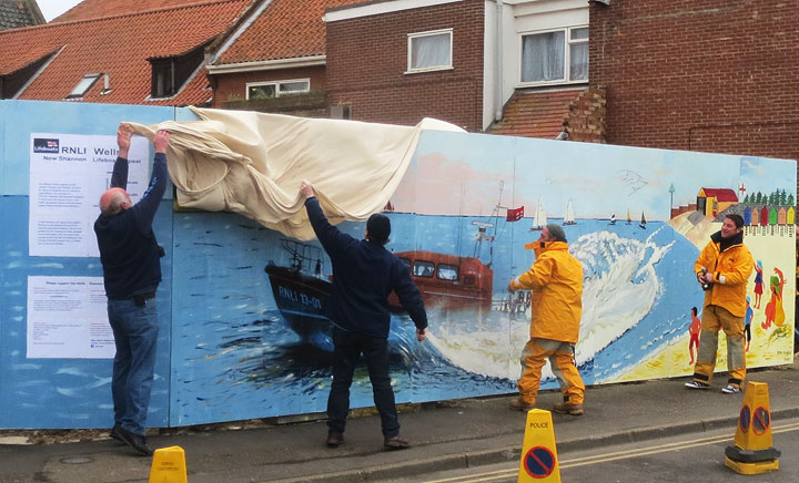 Crew members unveil the mural