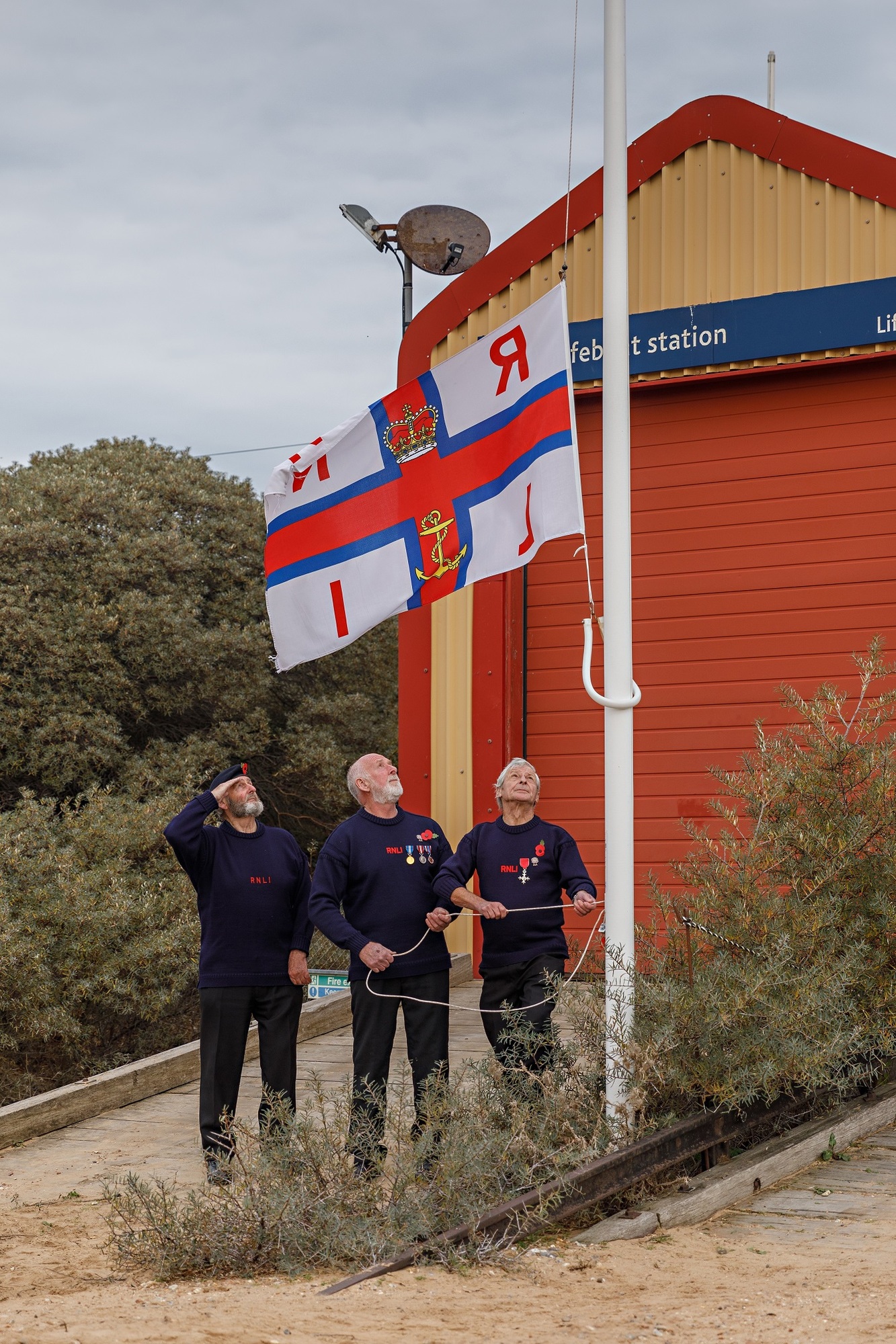 Billy Scoles, Fred Whitaker and Phil Eaglen lower the flag on the old boathouse