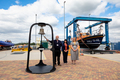 Invited long-serving RNLI volunteers prepare to ring the bell to mark the completion of the build of the new boat