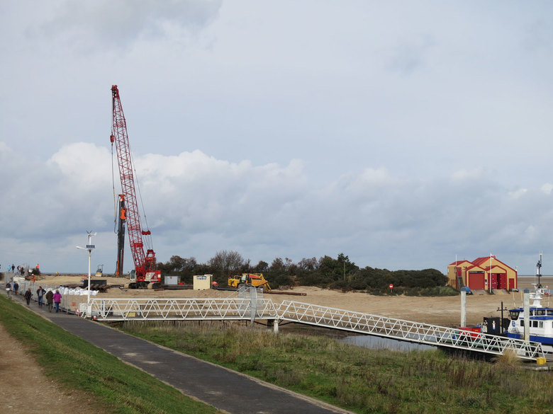 Piling rig in place on the beach for piling with the crane passing the tubular steel piles over the sea defences