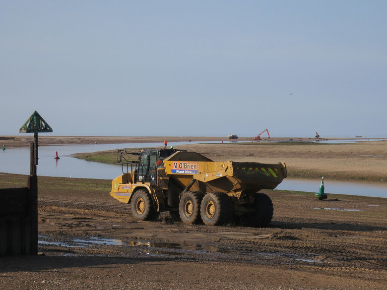 Material dredged by Wells harbour from the channel is ferried back to the site across Wells beach