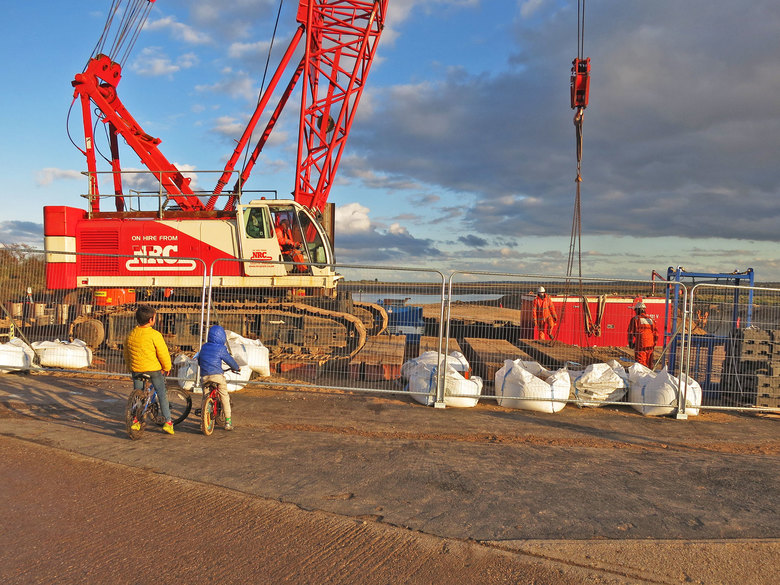 The crane changing position on site, moving its own supporting mat piece by piece as it goes