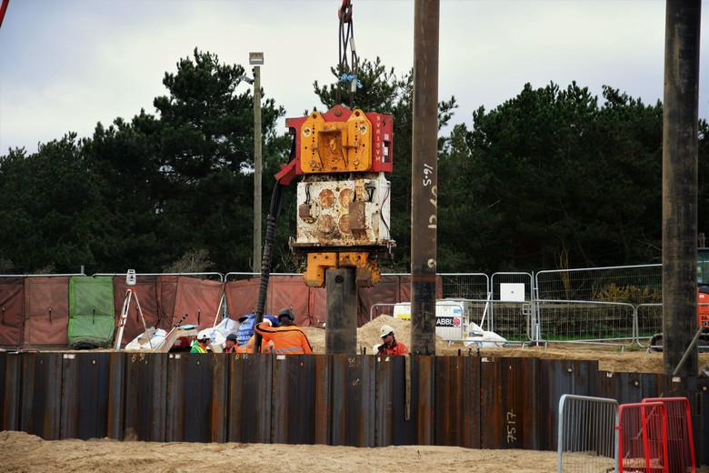 Vibro head suspended from the crane being used to drive piles in