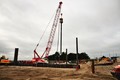 Vibro head suspended from the crane being used to drive piles in