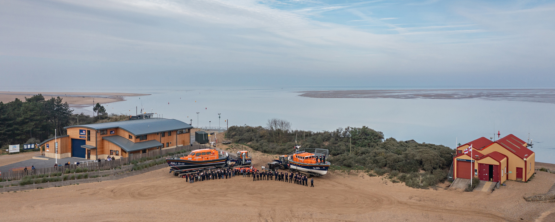 All three boats and both boathouses plus crew, family and friends together on the beach