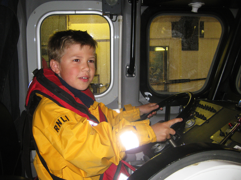 James Dye at the helm of the Mersey class while visiting to donate a welly-full of money collected for the station