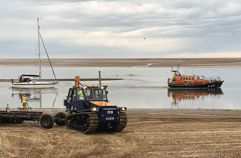 Lifeboat with 'Thalmia' in tow passing the boathouse on the last of the tide