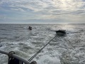 Sunken boat being towed onto the beach for recovery